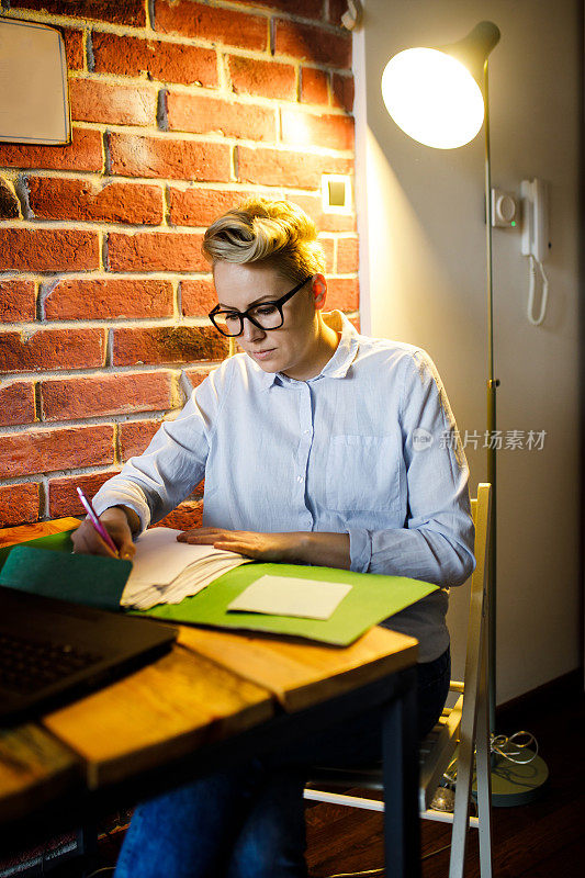 一名年轻的女企业家，在家办公，坐在办公桌前用笔记本电脑打字。
