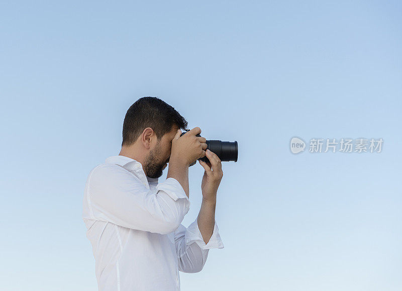 男性摄影师正在拍摄一张照片的蓝天背景与复制空间