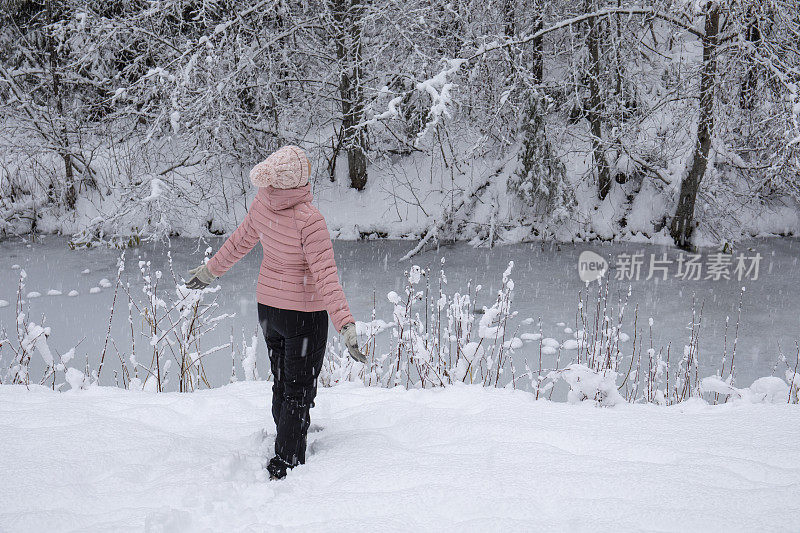 女徒步旅行者在白雪覆盖的河岸放松