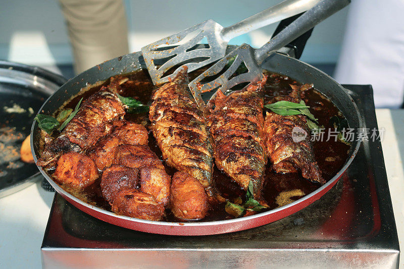 金属夹子把鱼煎得酥脆，在热锅上煎，goanfish咖喱食谱