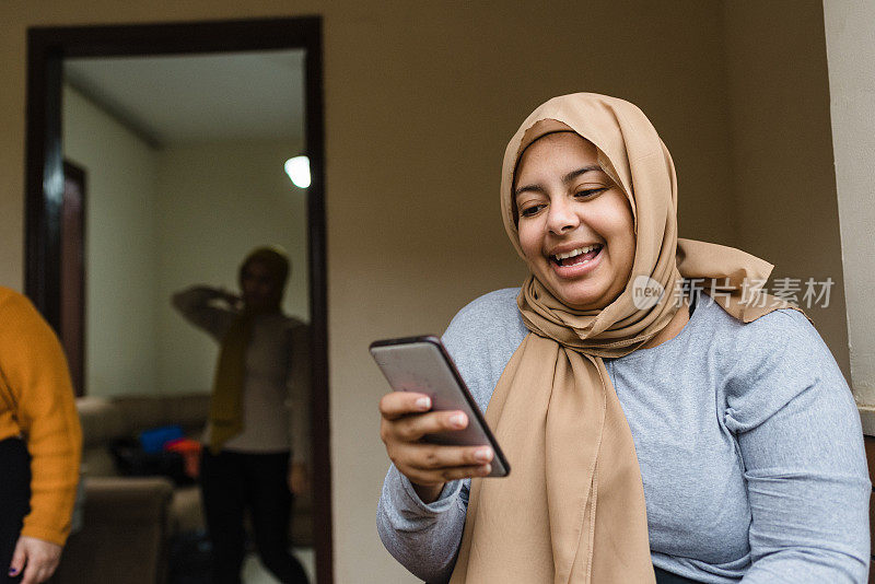 微笑的穆斯林妇女使用智能手机