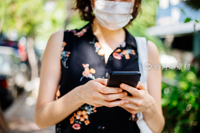 年轻女子戴着口罩在街上打电话