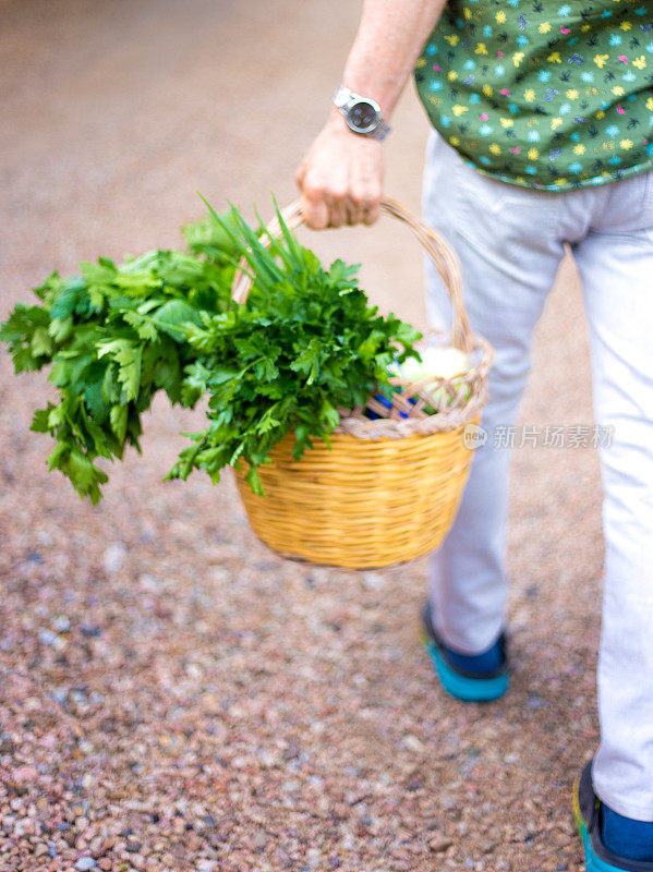 一名男子提着满满一篮绿色蔬菜行走