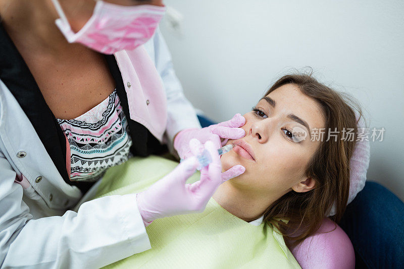 年轻女子正在嘴唇上注射透明质酸