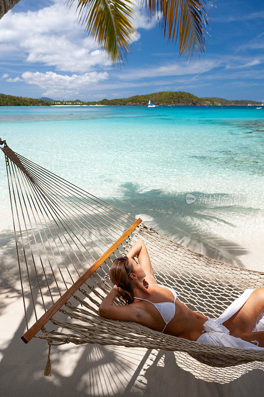 一名女子在原始热带海滩的吊床上放松