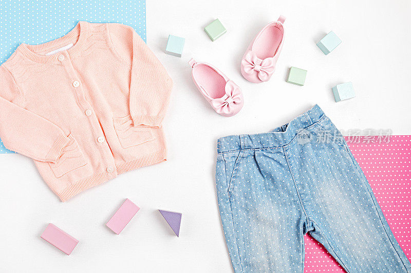 搭配粉红色的婴儿开衫，牛仔裤和鞋子在蓝色，粉色和白色的背景。现代女人的衣服