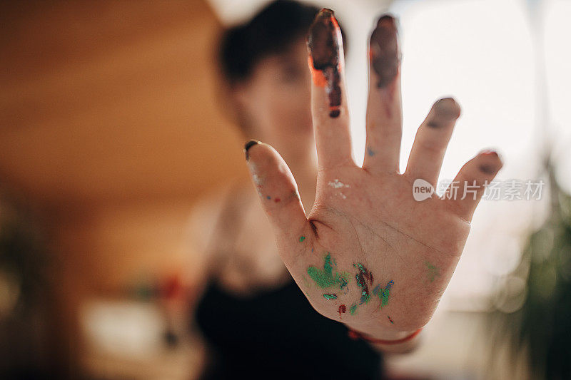 可爱的女艺术家展示她的脏手从绘画与它