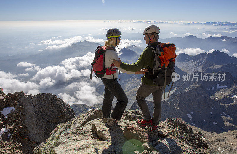 一对登山夫妇站在山顶上，望向远方