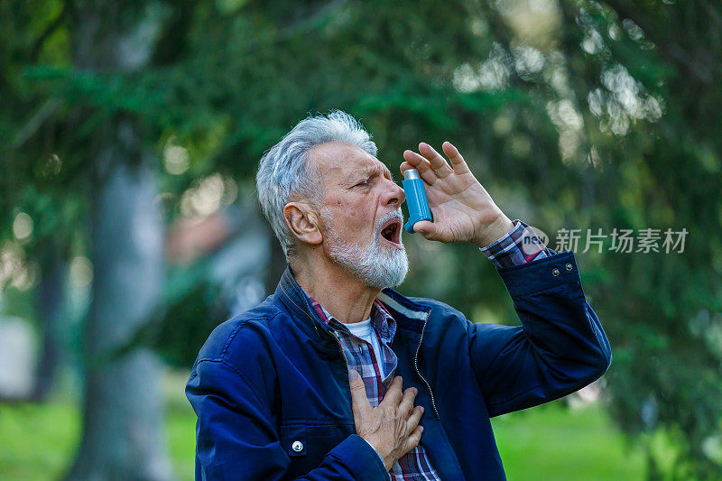 一位有呼吸问题的老人正在户外使用哮喘吸入器。