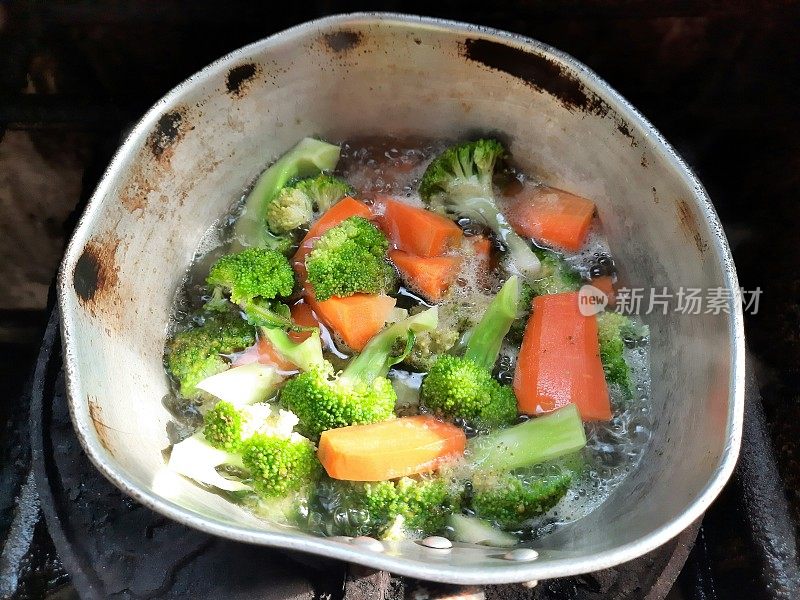 在炉子上用热水煮胡萝卜和花椰菜-食物准备。