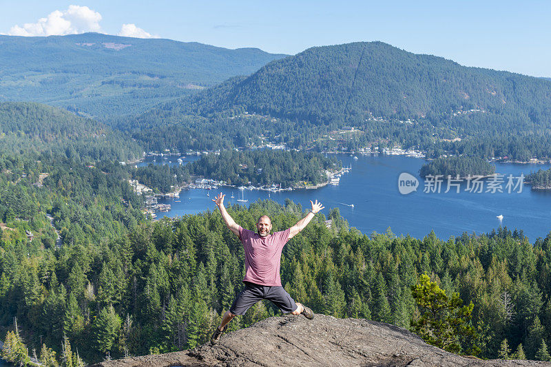 在阳光明媚的登山山顶，人高兴地跳了起来