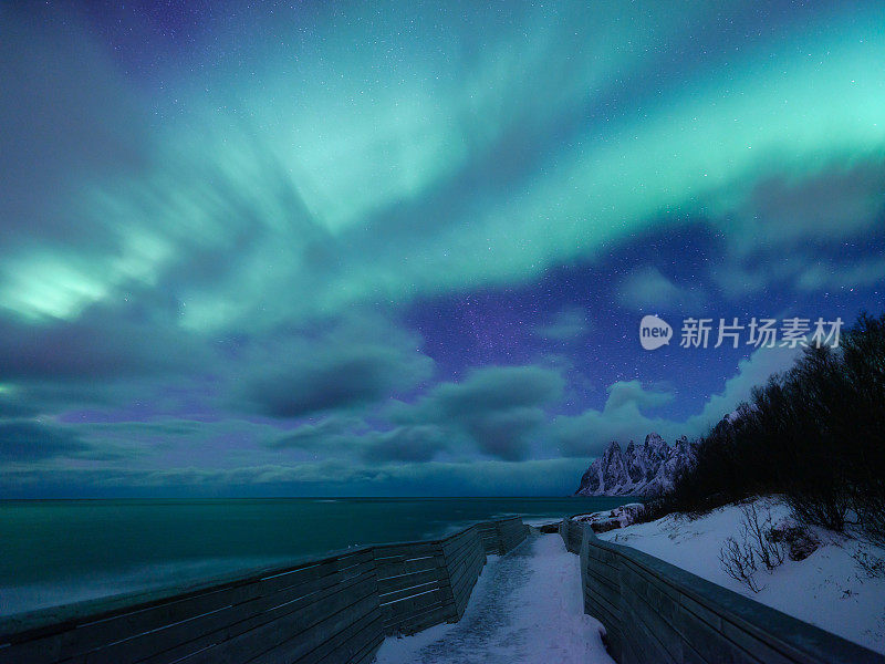 东洋背景岩石和北极光。Senja群岛,挪威。恒星轨迹和北极光。水面上的倒影。旅游形象