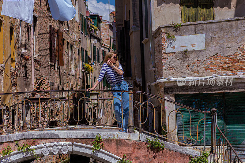 美丽的女游客站在威尼斯的一座桥上