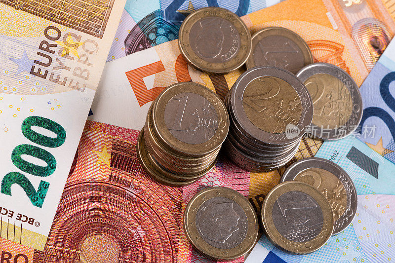 1欧元和2欧元面额的硬币，背景是不同面额的欧元钞票
