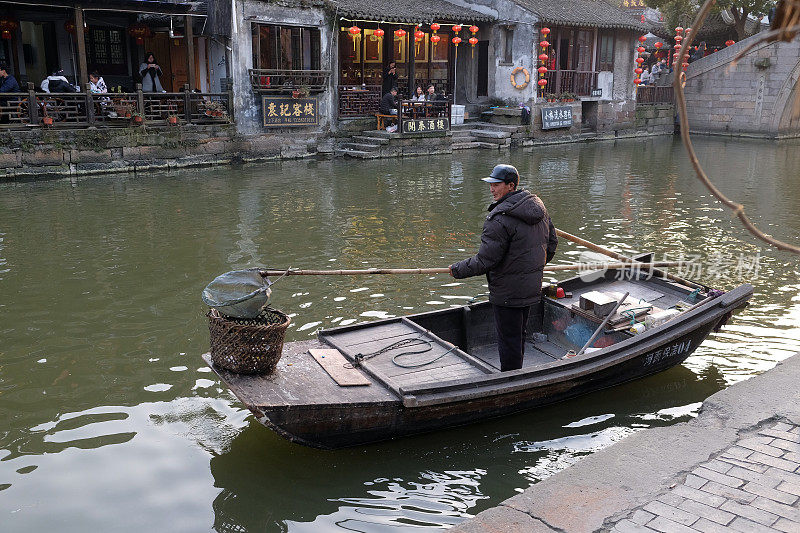 在中国浙江省西塘镇的运河上，一名男子乘坐古老的木船