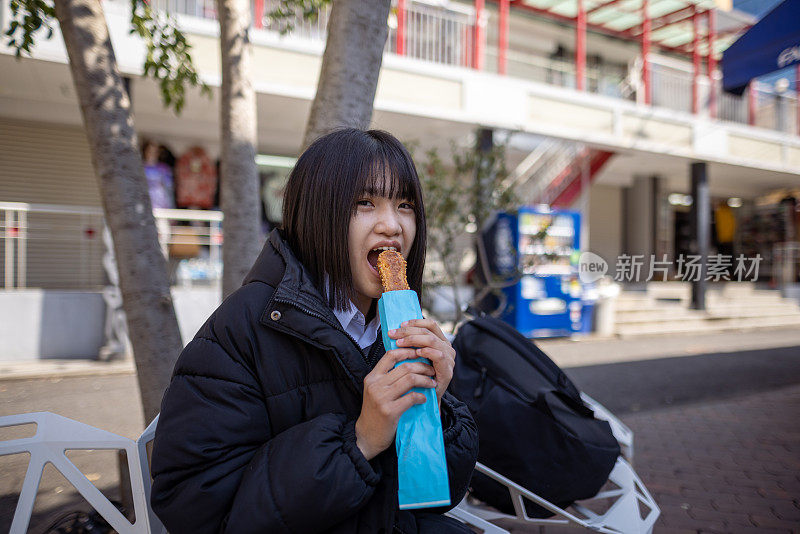 十几岁的女孩在街上吃零食