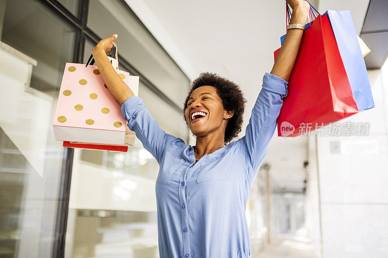 快乐的女人举起双臂，举起购物袋