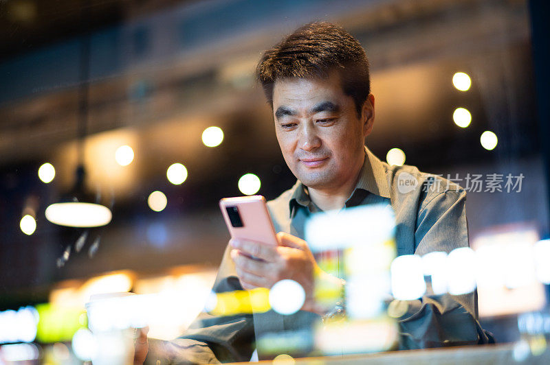 亚洲中年男子在咖啡店使用智能手机