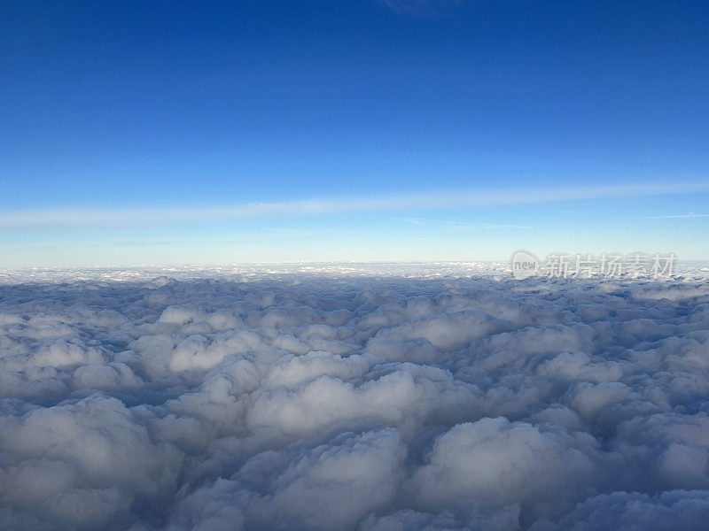 从飞机窗口看出去。美丽的云景配上蓝天。透过一架飞机的窗户，看到白云上方的美丽全景。乘飞机旅行的概念