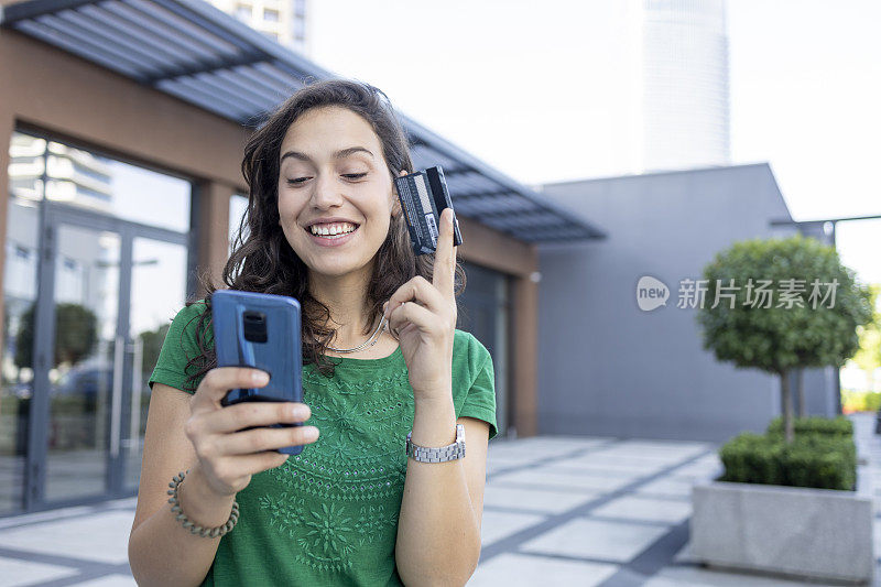 年轻女子微笑着在网上购物，用信用卡支付