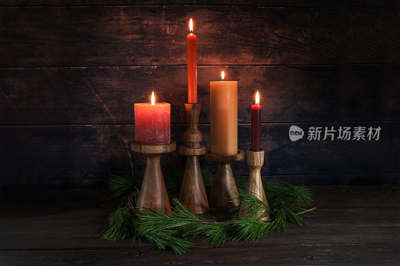 四种不同的蜡烛在暖色的木制支架上为降临节与一些松树树枝在一个黑暗的乡村背景的木头，复制空间