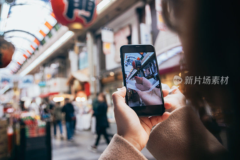 一名亚洲女子正在日本大阪的黑门市场观光，享受当地的美食。