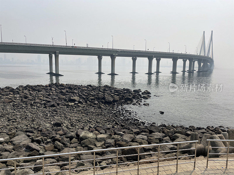 印度孟买班德拉-沃利海路(拉吉夫甘地海路)的特写图片，混凝土、斜拉桥、海水、八车道高架桥、柱子、烟雾