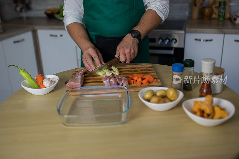 在厨房里为晚餐切菜和肉的年轻人特写。用爱烹饪。