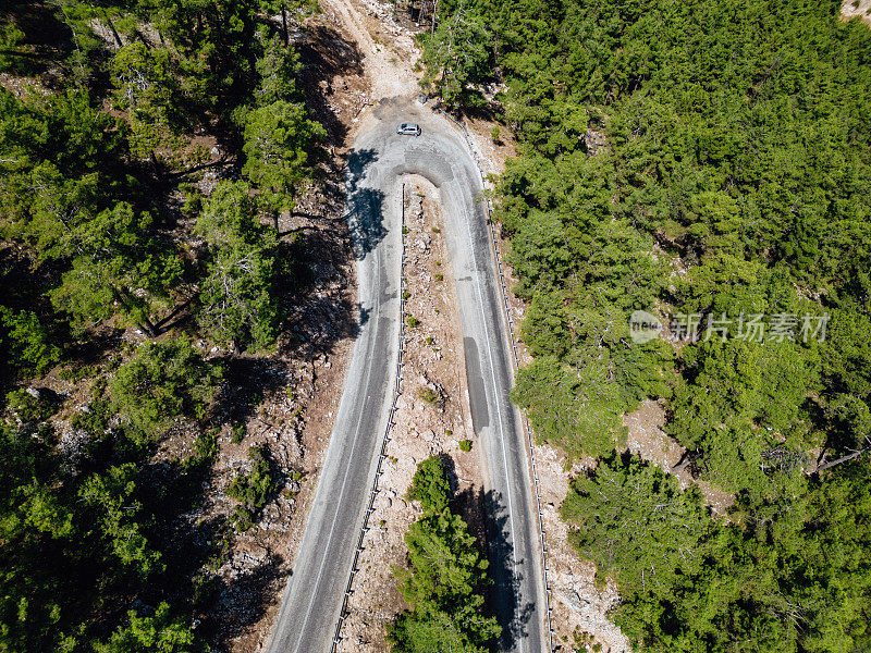 在森林山区的道路上行驶的车辆用无人机拍摄沥青弯道