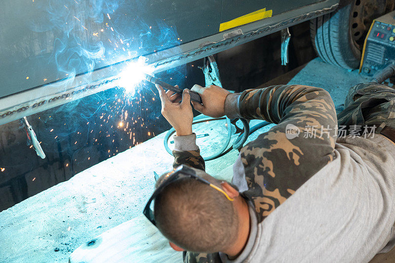 专业的汽车修理工用电焊机修理汽车。