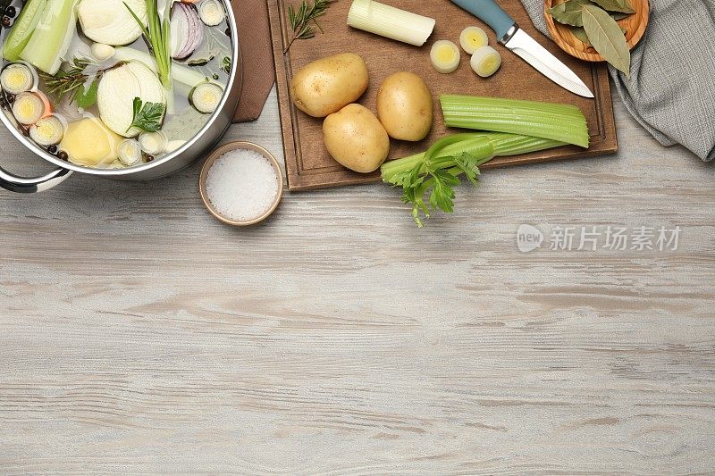 锅和不同的食材烹饪美味的清汤放在白色的木桌上，平铺。文本空间
