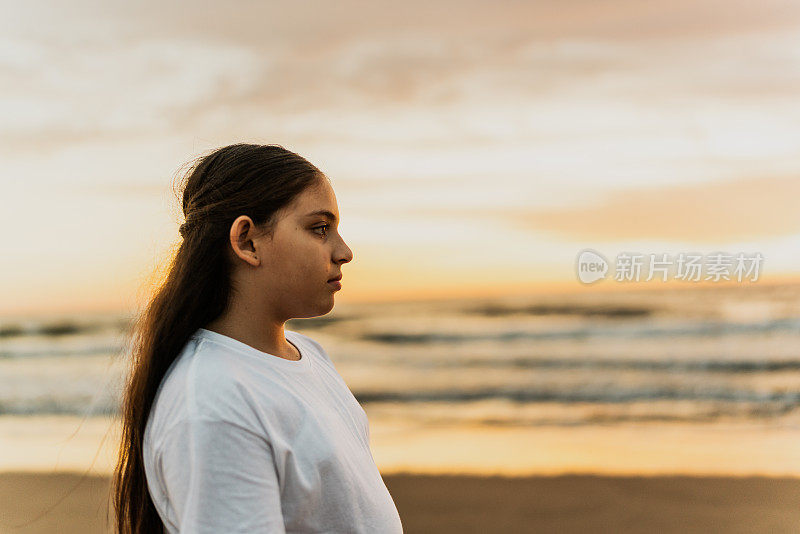 小女孩望着别处，在海滩上沉思