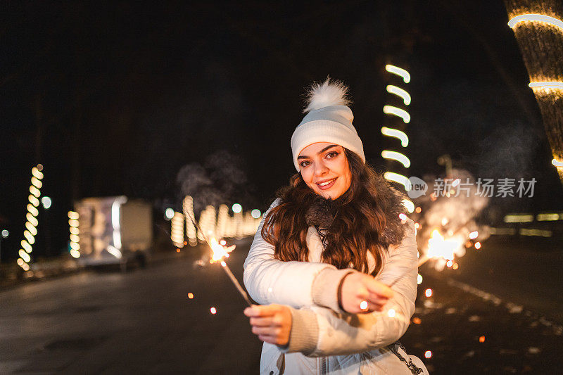 美丽的年轻女子手持烟花在户外庆祝除夕