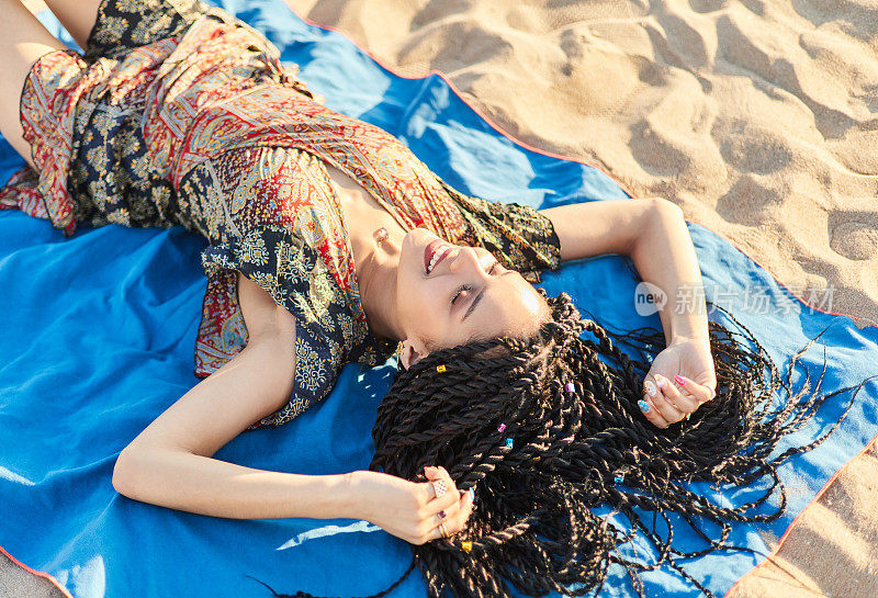 一个梳着辫子的拉丁美洲女人悠闲地躺在沙滩上。