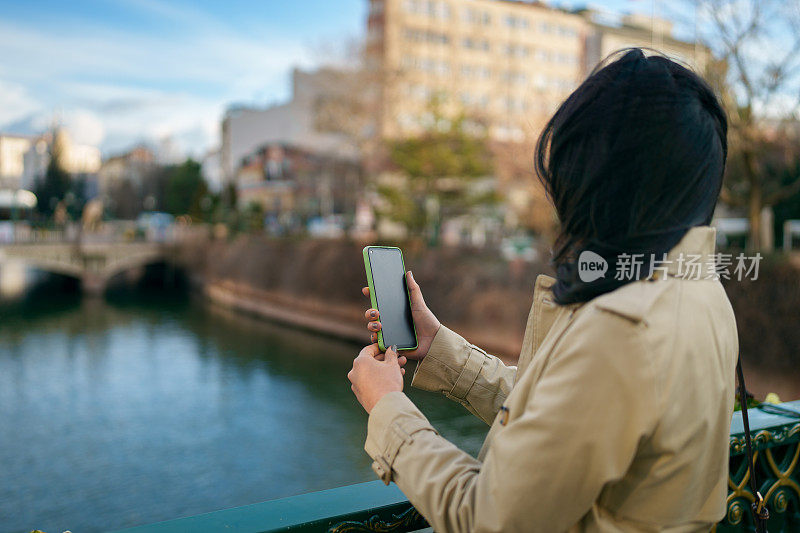 亚洲女人用手机拍照，在城里旅行。