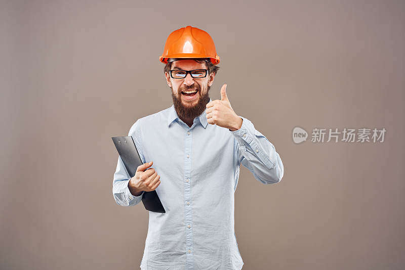 工业文件上戴着橙色安全帽的情绪化男子