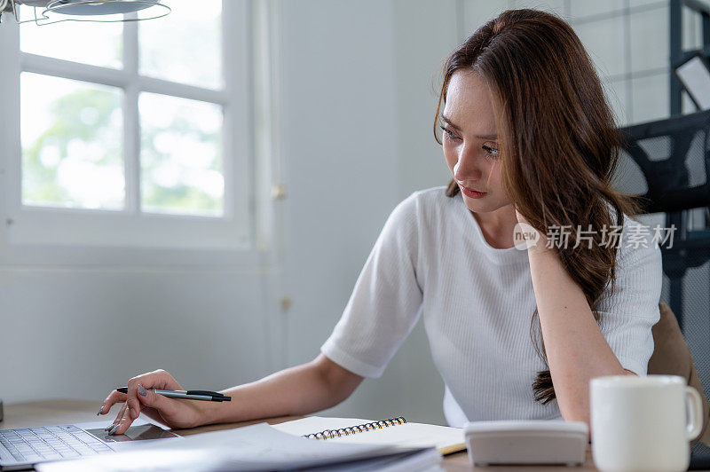 一位女商人在家庭办公室专注于工作时，看起来压力很大，而且头痛。