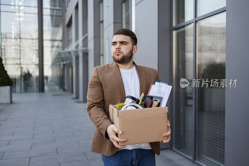 驾驭变化:失业后，男人离开办公室，随身带着私人物品