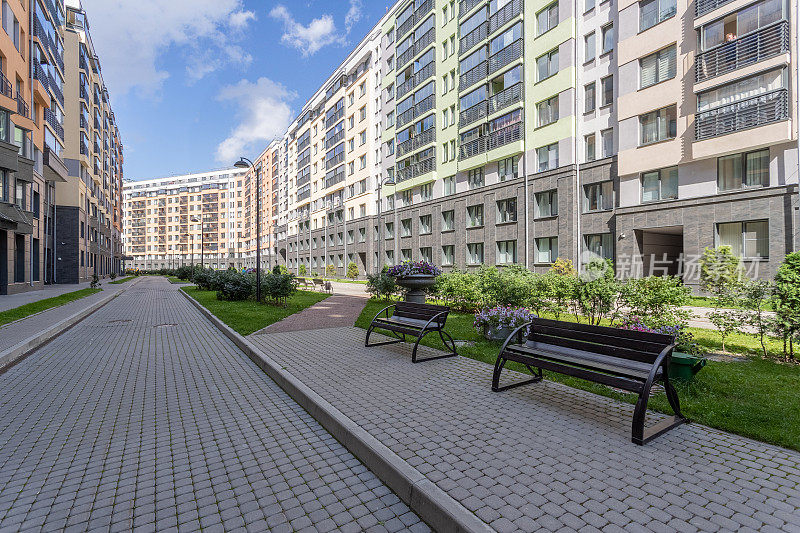 一个带有长椅和绿色花坛的住宅综合体庭院，周围环绕着多层建筑。