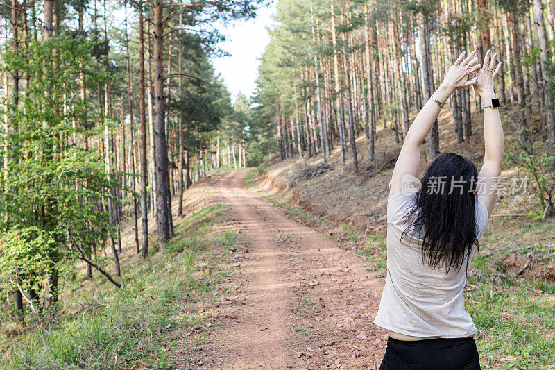 快乐的女跑步者正在森林里阳光明媚的小路上享受慢跑或越野跑。