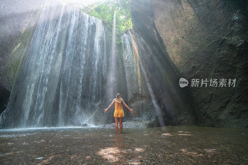 在巴厘岛的热带雨林中，旅行的年轻女子张开双臂拥抱大自然的美丽。人们以自然为旅游理念。