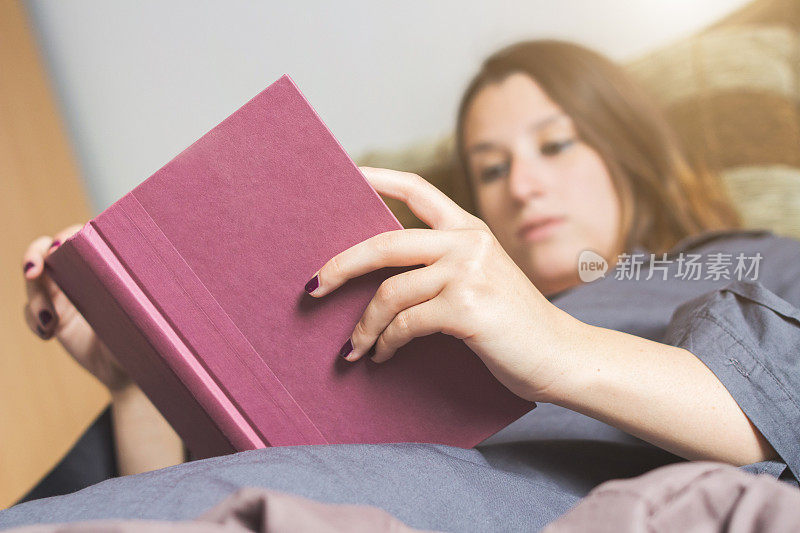 躺在床上看她最喜欢的书的女人