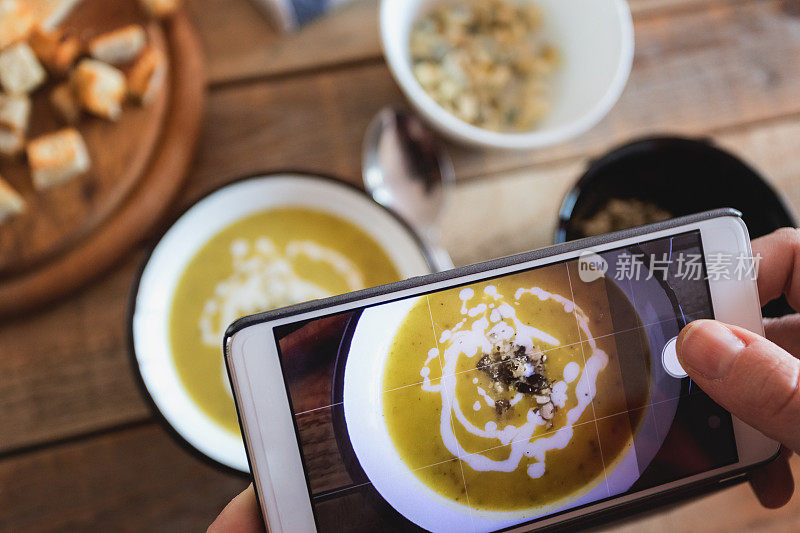 美食博客，拍摄花椰菜奶油汤加南瓜子和烤面包在金属盘子里的照片