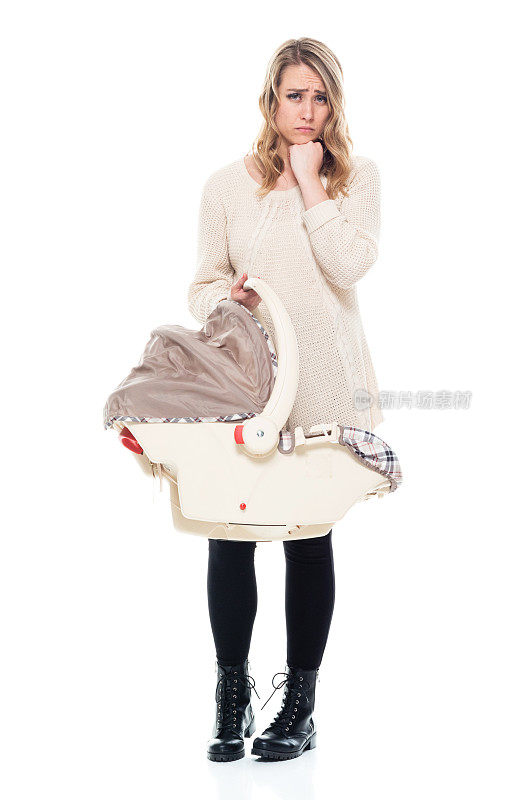 年轻漂亮的妈妈穿着毛衣抱着婴儿汽车座椅-悲伤