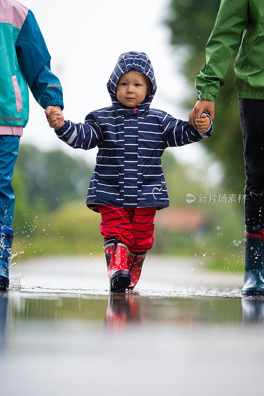 可爱的小女孩和其他孩子在雨中散步