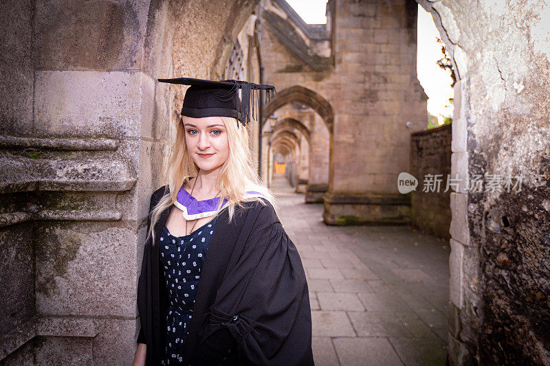 一位年轻自信的女毕业生在温彻斯特的毕业会场。期待一个光明的未来。温彻斯特大教堂的拱顶走廊渐渐远去
