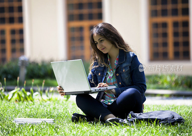 一个年轻女子在学校的花园里上网