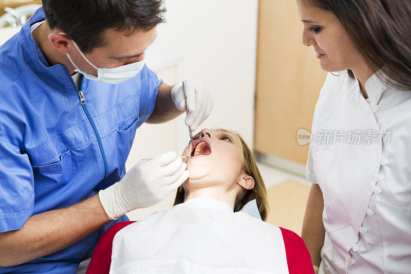 牙医和他的助手一起工作女性患者