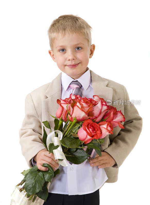 可爱的小绅士拿着一大束红玫瑰站在那里。