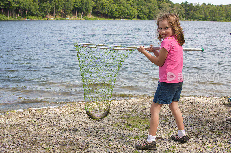 年轻的女孩和鳟鱼在她的渔网